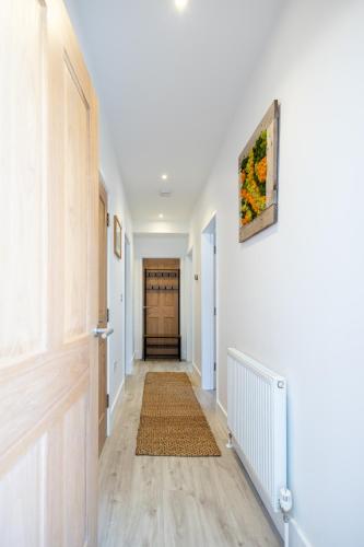 a hallway with white walls and a door with a rug at The Ramey in Sheringham