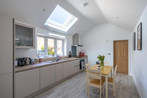 a kitchen with white cabinets and a table and a skylight at The Ramey in Sheringham