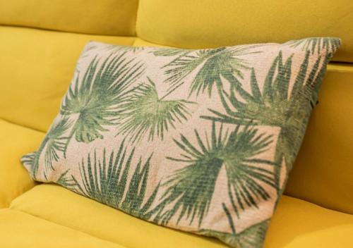 a pillow with palm trees on it sitting on a couch at Apartamento céntrico con wifi y parking de coche tamaño medio in Cangas de Onís