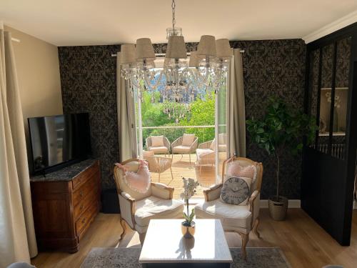 a living room with a chandelier and a table and chairs at Villa Agatha in Épinal