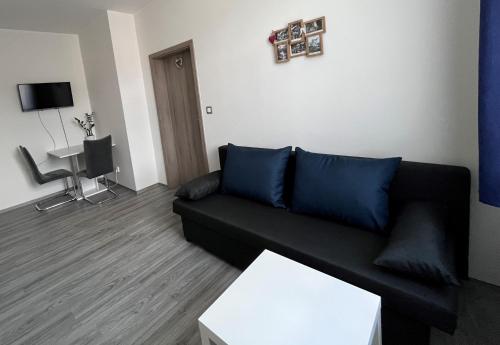 a living room with a black couch and a table at Apartmán na výsluní in Luhačovice