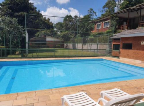 a large swimming pool with two lawn chairs next to it at Casa aconchegante com vista para as montanhas in Teresópolis
