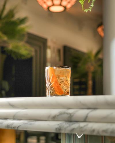 a glass of orange liquid sitting on a table at The Municipal Hotel Liverpool - MGallery in Liverpool