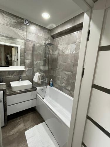 a bathroom with a bath tub and a sink at Dendrarium Park Apartment in Chişinău