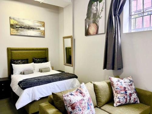 um quarto com uma cama, um sofá e uma cama em Matcha themed Apartment in City em Joanesburgo