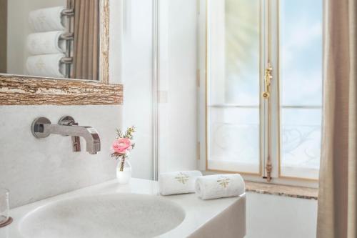 a white bathroom with a sink and a mirror at La Nauve, Hôtel & Jardin - Relais & Châteaux in Cognac