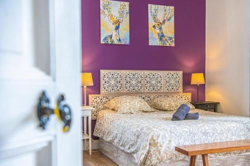 une chambre avec un lit avec un mur violet dans l'établissement Grand 2 chambres avec balcon Parc Longchamp, à Marseille