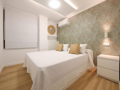 a bedroom with a large white bed and a window at Esmeralda Beach in Torrevieja