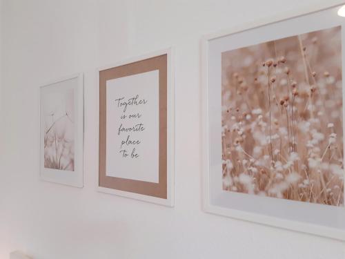 trois images encadrées sur un mur avec des fleurs dans l'établissement FeWo Greiwe, à Telgte