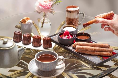 a glass table with a tray of desserts and a cup of tea at La Nauve, Hôtel & Jardin - Relais & Châteaux in Cognac