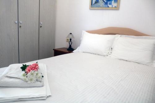 a white bed with a bouquet of flowers on it at Ammoudeli Apartments in Plomarion