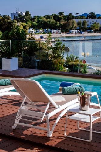 two white chairs sitting on a deck next to a swimming pool at Dedaj Resort - Villa Auri in Zadar