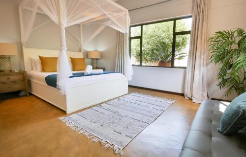 a bedroom with a canopy bed and a couch at Victoria Falls Holiday Home in Victoria Falls