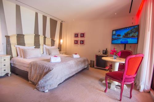 a bedroom with a bed and a table and a tv at Boutique Hotel Vivenda Miranda in Lagos