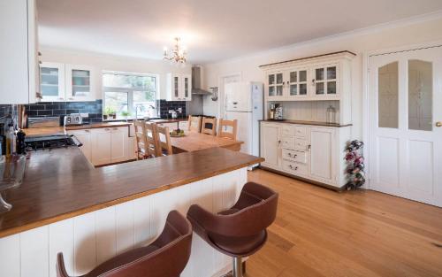 a kitchen with white cabinets and a wooden counter top at Luxurious 5 bedroomed home with sea view close to beach in Lettermacaward