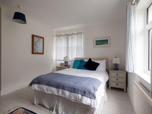 a white bedroom with a bed and a window at Luxurious 5 bedroomed home with sea view close to beach in Lettermacaward