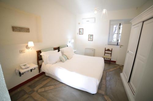 a bedroom with a large white bed and a chair at Castello di Serragiumenta in Firmo