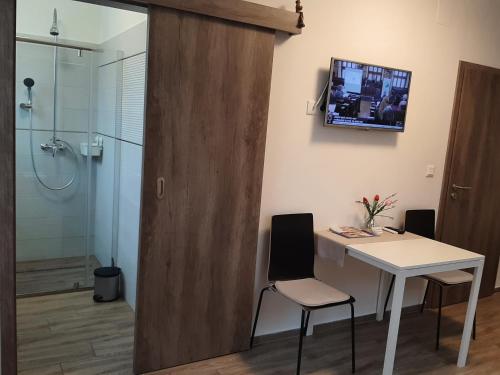 a bathroom with a desk and a shower with a television on the wall at Patak Vendégház in Zalaegerszeg