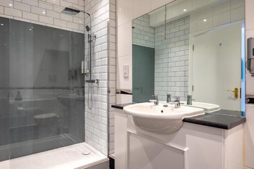 a white bathroom with a sink and a shower at White Lion Royal Hotel in Bala