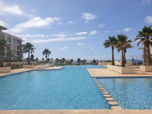 uma piscina com palmeiras e um edifício em Superbe appartement vue sur mer em Salé