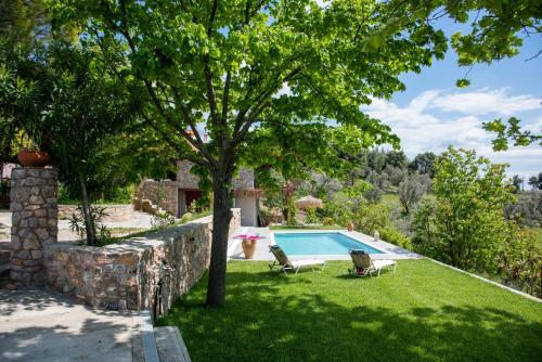 a pool in a yard with two chairs and a tree at Calypso Villa with Jacuzzi Pool & Sea View in Nerotriviá