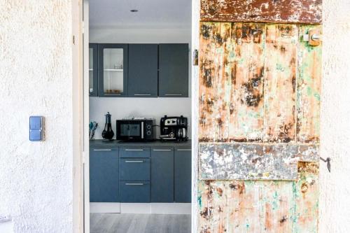 une cuisine avec des armoires bleues et une porte rouillée dans l'établissement Pieds dans l'eau - Terrasse vue mer 2 chambres, à Le Rove