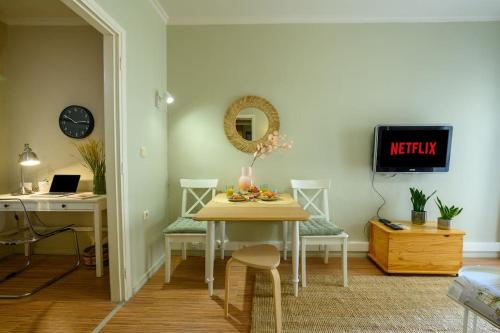 a dining room with a table and chairs and a tv at Meraki down town apartment in Ágios Rókkos