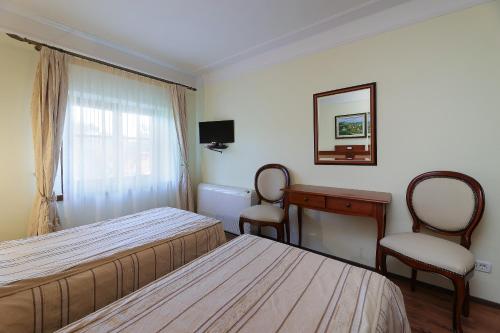 a bedroom with two beds and a desk and two chairs at B & B Casa Rustica Dva Baladura Rooms in Kanfanar