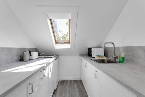 cocina blanca con fregadero y ventana en Central and Cozy Apartment, en Reikiavik