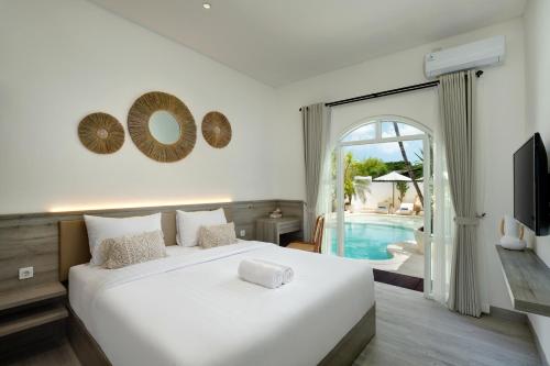 a bedroom with a white bed and a pool at Kemari Studio in Canggu