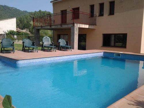 uma piscina com cadeiras e uma casa em Casa St Llorenc de la Muga em Sant Llorenç de la Muga