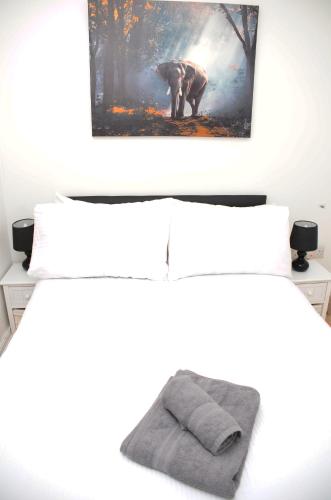 a bedroom with a bed with a painting on the wall at 29EW Dreams Unlimited Serviced Accommodation- Staines - Heathrow in Stanwell