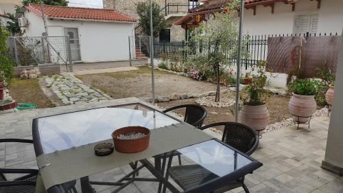 a patio with a glass table and chairs in a backyard at Nikolas House - ΤΟ ΣΠΙΤΙ ΤΟΥ ΝΙΚΟΛΑ in Archea Pissa