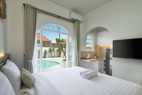 a bedroom with a large white bed and a kitchen at Kemari Studio in Canggu