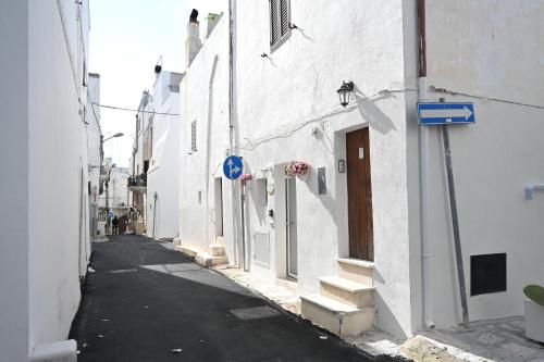 an alley with white buildings and a blue sign at CASA FLAMI' 4 in Ostuni
