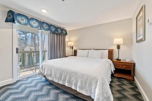 a bedroom with a large bed and a balcony at The Grand Hotel in Ogunquit