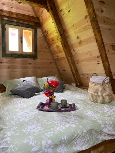 Una cama con una bandeja con dos tazas y flores. en Eco kutak 2 en Mojkovac