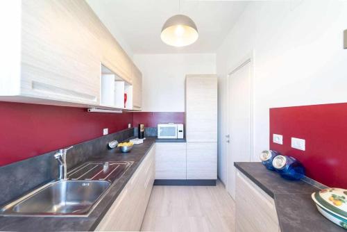 uma cozinha com um lavatório e uma parede vermelha em Blue Vibes em Alghero