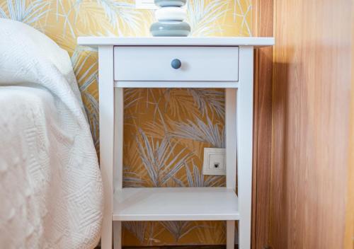 a white nightstand next to a bed in a bedroom at Apartamento céntrico con wifi y parking de coche tamaño medio in Cangas de Onís