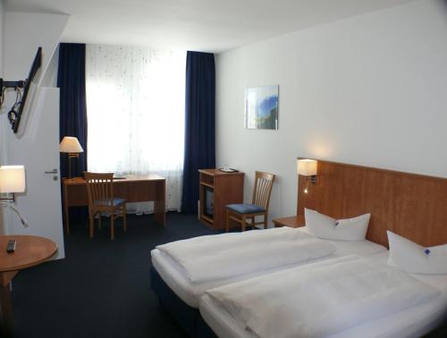 ein Hotelzimmer mit einem großen Bett und einem Schreibtisch in der Unterkunft Hotel Garni - Haus Gemmer in Coburg