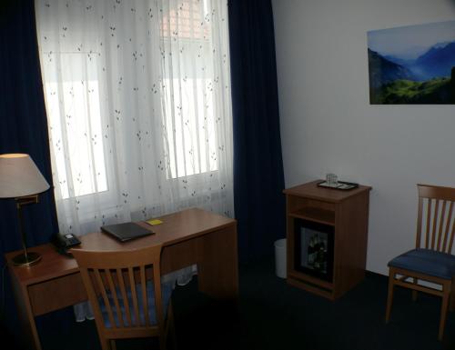 a room with a desk and a table and two windows at Hotel Garni - Haus Gemmer in Coburg