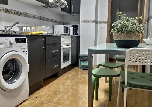 a kitchen with a washing machine and a table at Apartamento céntrico con wifi y parking de coche tamaño medio in Cangas de Onís