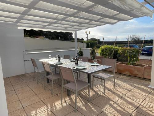 una mesa y sillas en un patio bajo una sombrilla blanca en Acquamarina 20, en Bergeggi