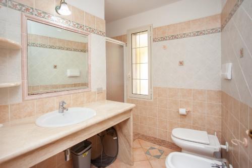 a bathroom with a sink and a toilet and a mirror at Appartamento Acacia in Cala Liberotto