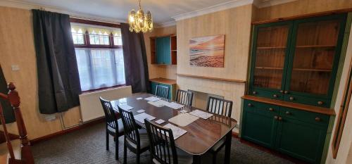 een eetkamer met een tafel met stoelen en een groene kast bij VH, 4 BR House, Upwell, Wisbech in Upwell