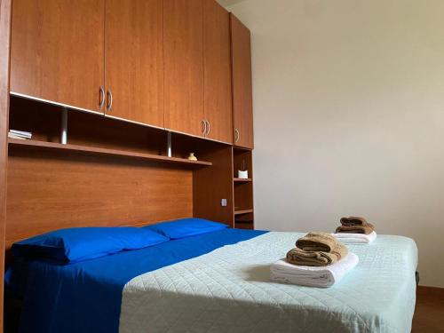 a bedroom with a bed with blue sheets and wooden cabinets at Casa Gaia in Avola