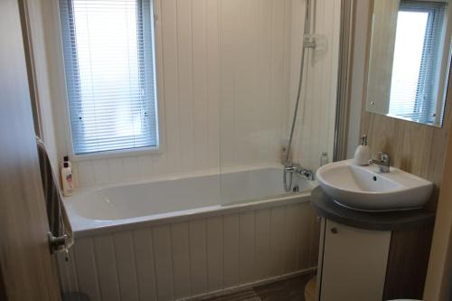 a bathroom with a tub and a sink and a bath tub at Platinum lodge on Carlton Meres holiday Park in Rendham