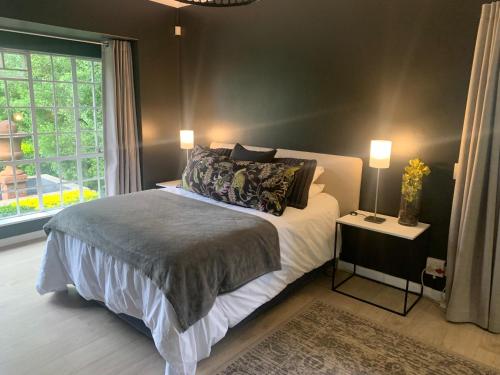 ein Schlafzimmer mit einem Bett und einem großen Fenster in der Unterkunft Nine Loch Guesthouse in Johannesburg