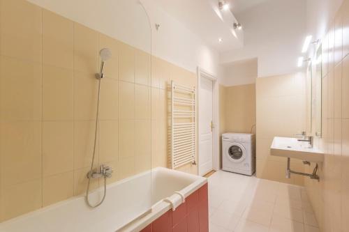ein Badezimmer mit einer Badewanne, einem Waschbecken und einer Waschmaschine in der Unterkunft Luxurious Art Deco Residence in the Heart of Budapest in Budapest