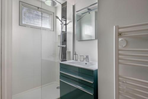 La salle de bains est pourvue d'un lavabo et d'une douche en verre. dans l'établissement Appartement moderne a 250 m de la mer, au Pouliguen
